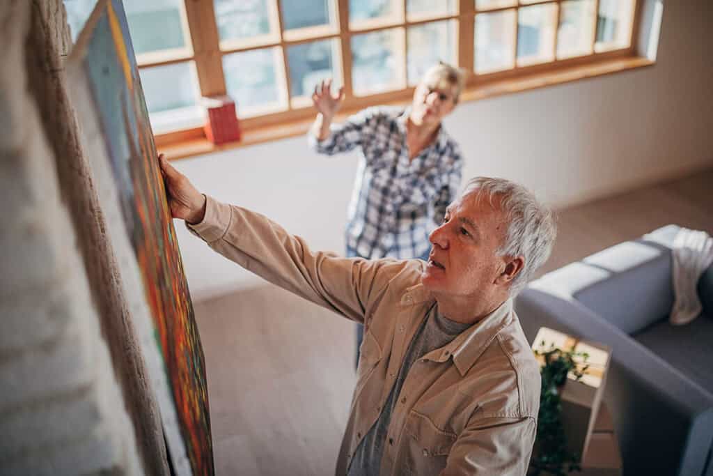 senior couple hanging up art in their new house